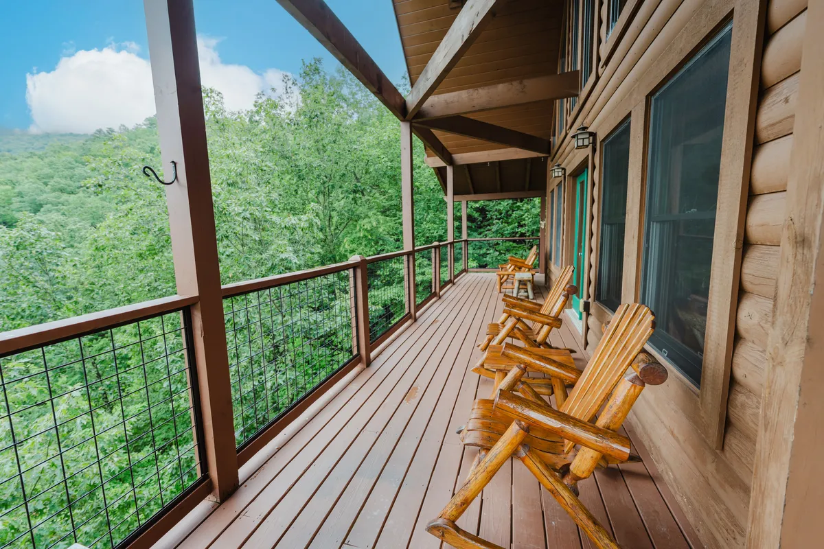 This image captures a relaxing outdoor deck with classic wooden rocking chairs overlooking lush greenery. The wooden railing frames the view, inviting guests to unwind and enjoy the natural surroundings. The peaceful setting hints at family moments spent outdoors after a day of adventures.